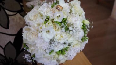 Güzel beyaz bir düğün buketinde iki altın alyans..