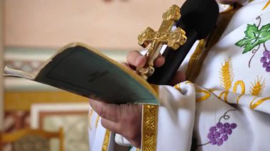 Elinde haç olan bir rahip ayin sırasında kitap okur..