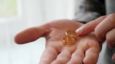 Bir adam avucunda iki altın alyans taşır. Düğün hazırlıkları..