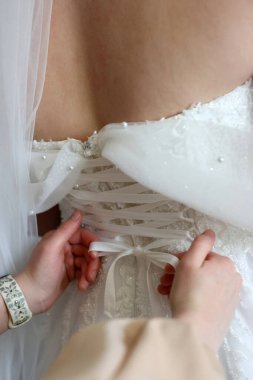 Gelinin arkadaşları onun gelinliğinin korsesini bağlayıp giyinmesine yardım ediyorlar..