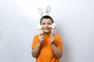 Tavşan kulaklı ve elinde süslü Paskalya yumurtaları tutan bir çocuk..