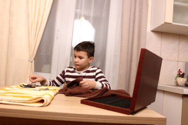 Oğlan çatal ve mutfak bıçaklarını siliyor. Ev işleri..