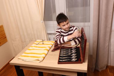 Oğlan çatal ve mutfak bıçaklarını siliyor. Ev işleri..