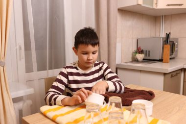 Oğlan bardakları ve bardakları havluyla siler. Ev işleri..