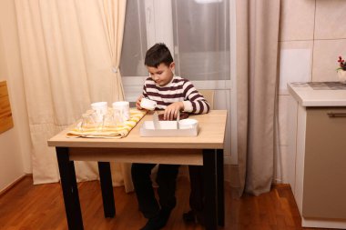 Oğlan bardakları ve bardakları havluyla siler. Ev işleri..