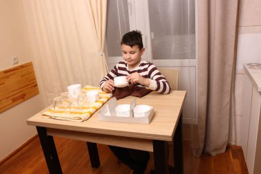 Oğlan bardakları ve bardakları havluyla siler. Ev işleri..