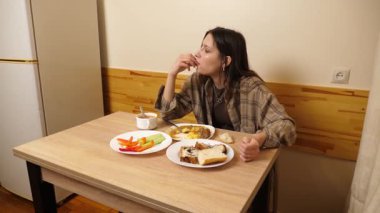 Güzel bir kız masada oturuyor, yiyor ve içiyor..