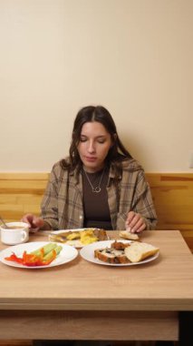 Güzel bir kız masada oturuyor, yiyor ve içiyor..