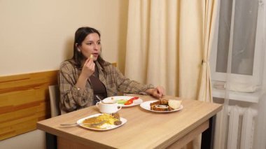 Güzel bir kız masada oturuyor, yiyor ve içiyor..