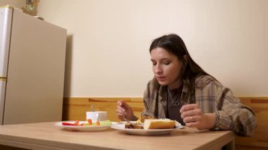 Güzel bir kız masada oturuyor, yiyor ve içiyor..