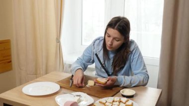 Peynirli ve sosisli sandviç hazırlayan kız. Ev yemeği..