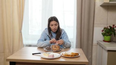 Kız kruvasan ve çikolata paketini boşaltıyor. Tatlı kahvaltı..