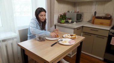 Kız kruvasan ve çikolata paketini boşaltıyor. Tatlı kahvaltı..