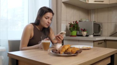 Kız masada oturuyor, kahve içiyor ve şeker yiyor..