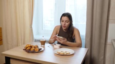 Kız masada oturuyor, kahve içiyor ve şeker yiyor..