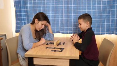 Bir kız küçük erkek kardeşiyle domino oynar. Boş oyunlar.