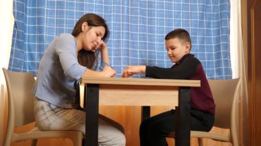 Bir kız küçük erkek kardeşiyle domino oynar. Boş oyunlar.