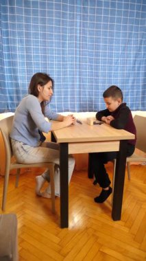 Bir kız küçük erkek kardeşiyle domino oynar. Boş oyunlar.