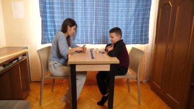 Bir kız küçük erkek kardeşiyle domino oynar. Boş oyunlar.