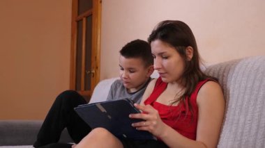 Erkek ve kız kardeş tablette oyun oynayıp patlamış mısır yiyorlar..