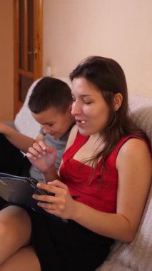 Erkek ve kız kardeş tablette oyun oynayıp patlamış mısır yiyorlar..