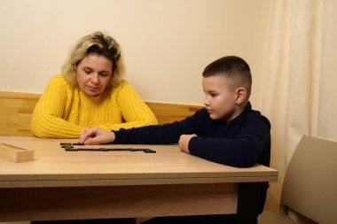 Anne ve oğlu masada domino oynuyorlar. Ev eğlencesi.