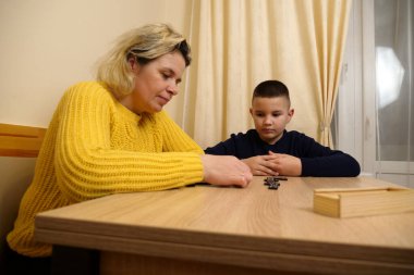 Anne ve oğlu masada domino oynuyorlar. Ev eğlencesi.