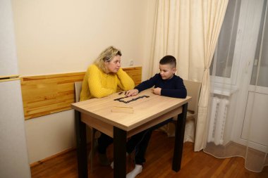 Anne ve oğlu masada domino oynuyorlar. Ev eğlencesi.