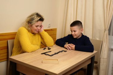 Anne ve oğlu masada domino oynuyorlar. Ev eğlencesi.