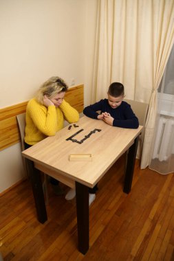 Anne ve oğlu masada domino oynuyorlar. Ev eğlencesi.