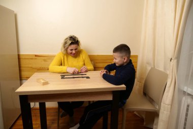 Anne ve oğlu masada domino oynuyorlar. Ev eğlencesi.