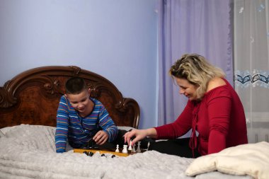 Anne ve oğlu kanepede otururken satranç oynuyorlar..