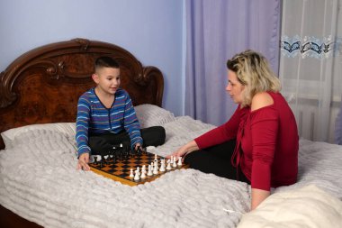 Anne ve oğlu kanepede otururken satranç oynuyorlar..