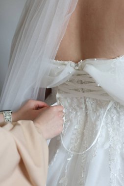 Gelinin giyinmesine yardım ederken arkadaşları gelinliğinin korsesini bağlıyorlar..