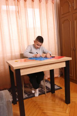 Bir çocuk masada otururken renkli kağıtlardan başvuru yapıyor. Yaratıcılık ve eğlence kavramı.