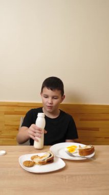 Bir adam masada otururken hamur işi yer, çay içer ve yoğurt içer..