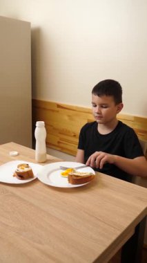 Bir adam masada otururken hamur işi yer, çay içer ve yoğurt içer..