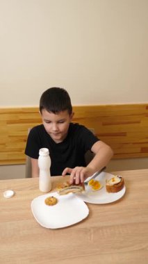 Bir adam masada otururken hamur işi yer, çay içer ve yoğurt içer..