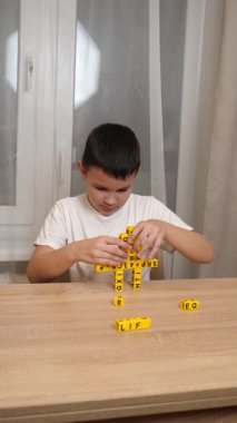 Bir çocuk masada otururken küplerden kelimeler üretiyor..