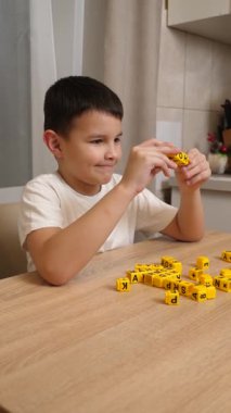 Bir çocuk masada otururken küplerden kelimeler üretiyor..