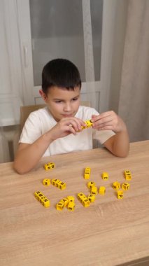 Bir çocuk masada otururken küplerden kelimeler üretiyor..