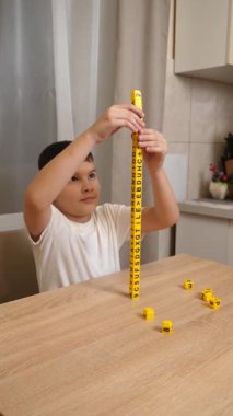 Bir çocuk masada otururken küplerden kelimeler üretiyor..