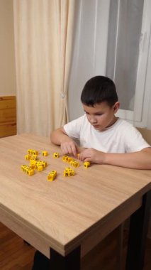 Bir çocuk masada otururken küplerden kelimeler üretiyor..