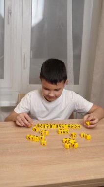 Bir çocuk masada otururken küplerden kelimeler üretiyor..
