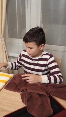 Oğlan çatal ve mutfak bıçaklarını siliyor. Ev işleri..