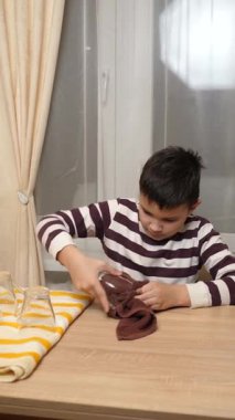Oğlan bardakları ve bardakları havluyla siler. Ev işleri..