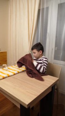 Oğlan bardakları ve bardakları havluyla siler. Ev işleri..