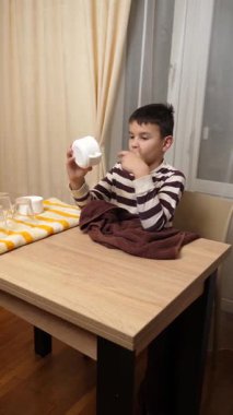 Oğlan bardakları ve bardakları havluyla siler. Ev işleri..