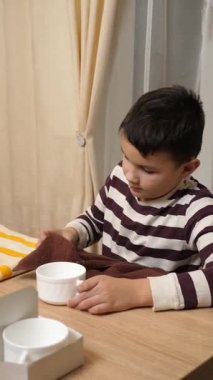 Oğlan bardakları ve bardakları havluyla siler. Ev işleri..