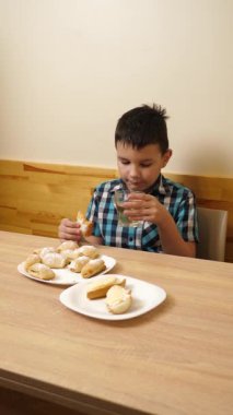 Bir çocuk masada otururken kurabiye yer ve çay içer..